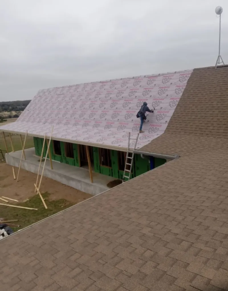 Worker preparing underlayment for a metal roof installation in Aurora